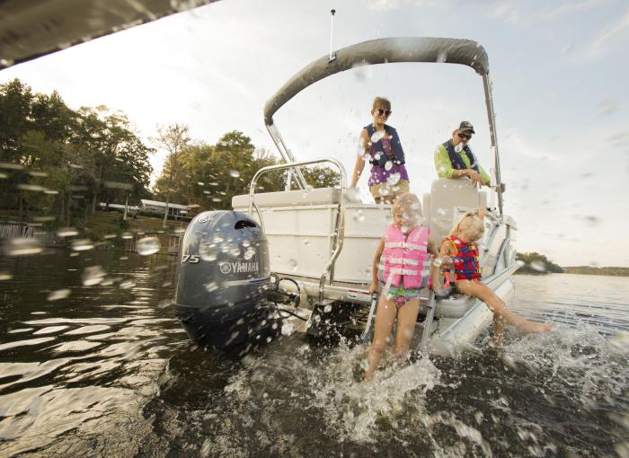 Kids splashing of the back of a pontoon boat powered by a Yamaha outboard engine